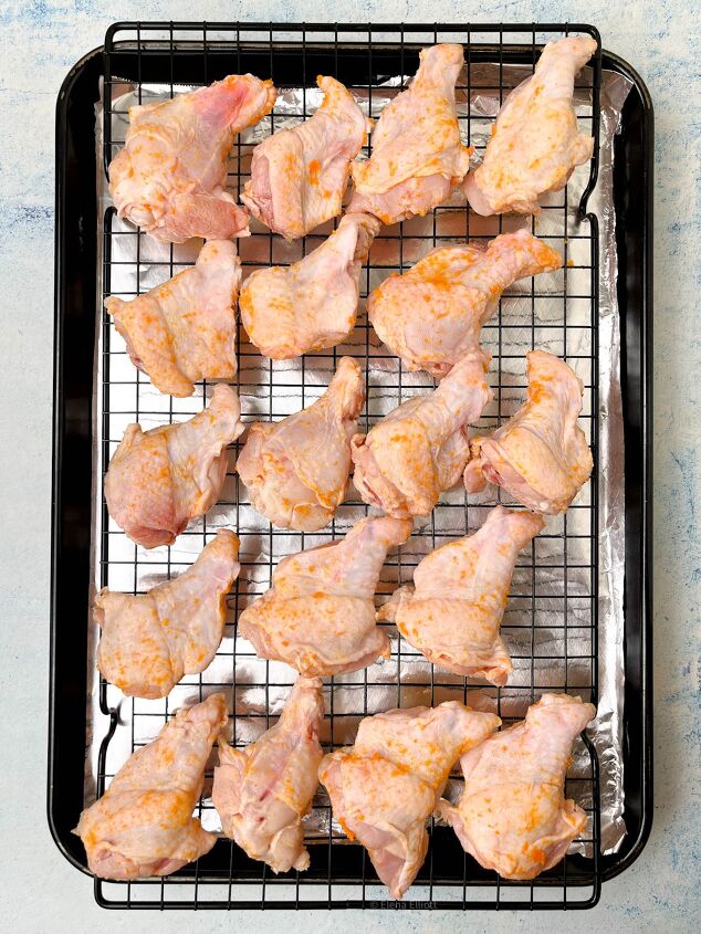 crispy salt and vinegar chicken wings recipe, Raw marinated chicken drumsticks coated with a light seasoning arranged on a wire rack over a baking sheet lined with foil The setup is on a light colored surface