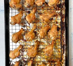 crispy salt and vinegar chicken wings recipe, Golden brown chicken drumettes arranged evenly on a wire rack over a foil lined baking tray The tray shows some oil and seasoning residue indicating they are freshly baked The background is a light blue surface