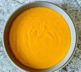curried lentil carrot soup, Golden yellow carrot and lentil soup are served in a round grey colored bowl which is placed on a table