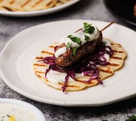 lamb kofta kebabs, Lamb kebab on a white plate next to meal components