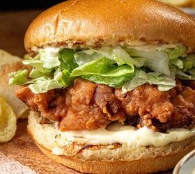 buttermilk crispy chicken sandwich, Close up of a crispy fried chicken sandwich with lettuce and mayonnaise in a soft bun The sandwich is placed on a wooden surface with potato chips on the side