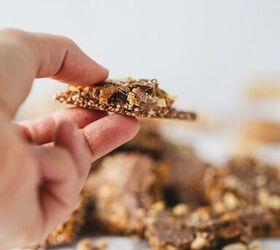 crunchy quinoa chocolate date bark a healthy ish sweet treat, hand holding a piece of date bark