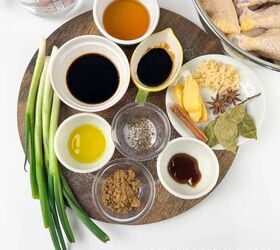 soy sauce braised chicken drumsticks flavorful one pot, A round wooden board displays various ingredients including soy sauces spices herbs and aromatics alongside a bowl of raw chicken drumsticks