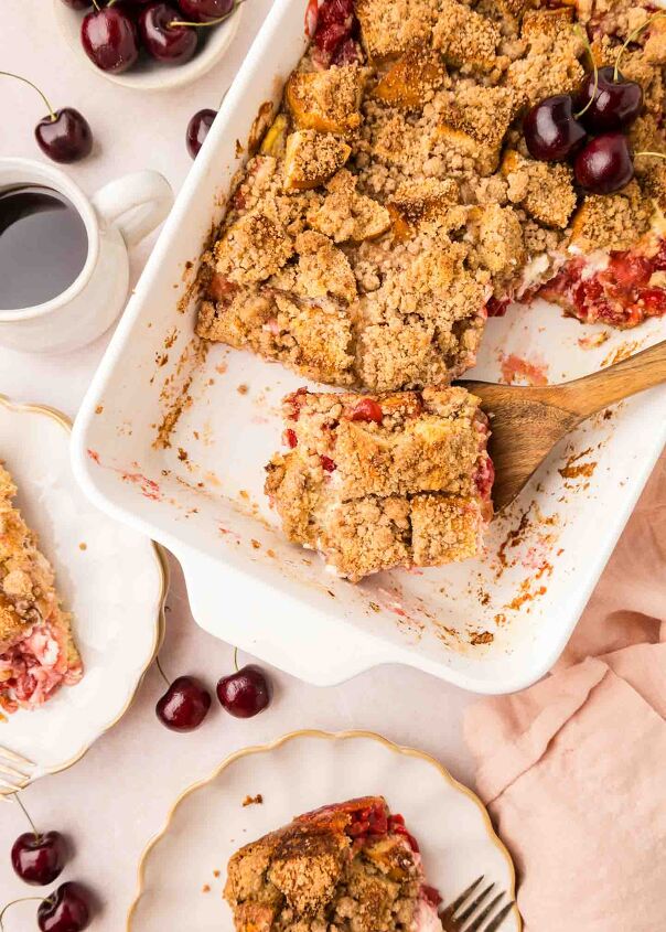 cherry cheesecake french toast casserole, french toast in a white dish with a piece on a wooden spoon