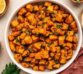crispy chicken caesar salad, Perfectly crispy sweet potato cubes sprinkled with parsley and sea salt in a white bowl along with dipping sauce lemon wedges in the sides