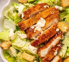 crispy chicken caesar salad, CLose up shot of crispy chicken caesar salad in a white bowl drizzled with salad dressing