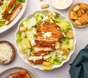 crispy chicken caesar salad, Crispy chicken caesar salad in a white bowl accompanied by a bowl homemade caesar salad dressing with parmesan cheese in a bowl on other side