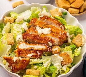 crispy chicken caesar salad, Black light shot of Crispy chicken caesar salad in a white bowl accompanied by a bowl homemade caesar salad dressing