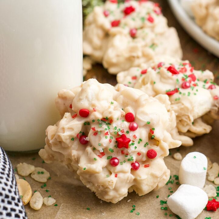 caramel cheesecake bars, Red and green decorated rice krispie cookies next to a carafe of milk on a piece of parchment paper