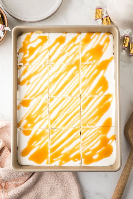 caramel cheesecake bars, Cool Whip and caramel sauce on top of the bars and sliced