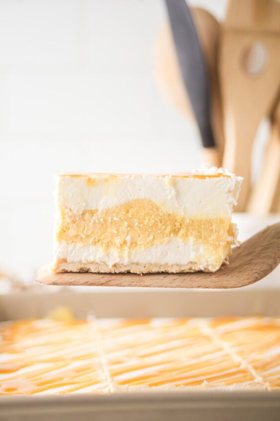 caramel cheesecake bars, A slice of caramel cheesecake bars on a wooden spatula to show the layers