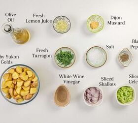 Ingredients for a salad are arranged on a white surface including olive oil lemon juice Dijon mustard fresh tarragon salt black pepper halved baby potatoes white wine vinegar sliced shallots and sliced celery each labeled