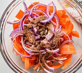 spicy carrot feta galette, Carrot ribbons sliced onions and spices in a glass mixing bowl