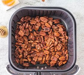 honey roasted pecans in air fryer, pecans in air fryer basket and honey and cinnamon sticks on top