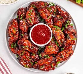 easy slow cooker korean chicken wings recipe, Korean chicken wings garnished with sesame seeds and green onions and a bowl of sauce