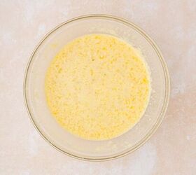 strawberry banana pancake casserole, A clear glass bowl filled with a mixture of beaten eggs and wet ingredients visible with bubbles and light froth on top sits on a beige countertop