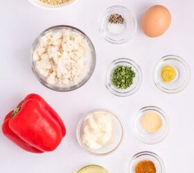 classic crab cake recipe little filler, Top down view of ingredients on a white surface including red bell pepper egg herbs spices mayonnaise oil bread crumbs parsley and chopped white seafood