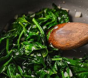 cajun crab spinach artichoke dip, Spinach wilting in a skillet with onions and garlic