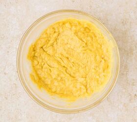 cake mix banana bread, A glass bowl filled with creamy yellow batter sits on a textured beige countertop
