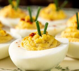 classic southern deviled eggs recipe, Deviled eggs arranged on a decorative plate each topped with chopped green garnish and a sprinkle of paprika