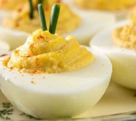 classic southern deviled eggs recipe, Close up of deviled eggs topped with chopped chives and paprika arranged on a patterned plate