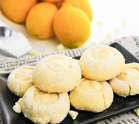 5 ingredient lemon white chocolate cookies with cake mix, A plate of lemon cookies displayed on a newspaper with a few lemons nearby