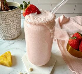 bahama mama smoothie tropical smoothie cafe copycat, A pink Bahama mama tropical smoothie in a glass with a strawberry garnish on top Pineapples strawberries white chocolate chips and shredded coconut around the glass