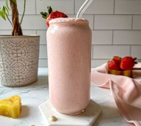 bahama mama smoothie tropical smoothie cafe copycat, A Bahama mama smoothie in a glass on a marble coaster with a frozen pineapple and strawberries on the countertop