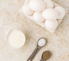 sheet pan eggs, A carton of white eggs a small pitcher of milk and two measuring spoons filled with salt and ground black pepper on a light textured surface