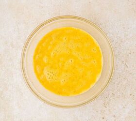 sheet pan eggs, A glass bowl containing beaten eggs sits on a light colored textured surface