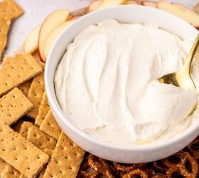 cool whip fruit dip, A bowl of creamy dip with a spoon is surrounded by sliced apples graham crackers and pretzels on a wooden board Apples and a strawberry are in the background