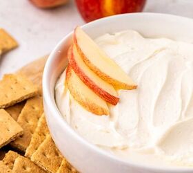cool whip fruit dip, A white bowl filled with creamy cool whip dip topped with apple slices is surrounded by graham crackers pretzels and two whole apples in the background