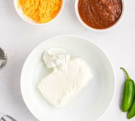 salsa and cream cheese dip, A bowl with cream cheese and sour cream a bowl of shredded cheddar cheese a bowl of salsa a hand mixer beater and two jalape os on a white countertop