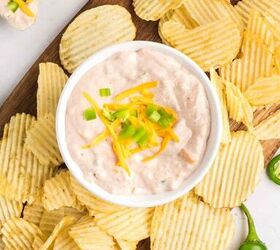 salsa and cream cheese dip, A bowl of creamy dip topped with shredded cheese and diced green onions is surrounded by ridged potato chips on a wooden board with whole and sliced jalape os nearby