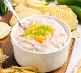 salsa and cream cheese dip, A white bowl of creamy dip topped with shredded cheese and diced green onions surrounded by ridged potato chips on a wooden board with jalape os and a striped cloth in the background