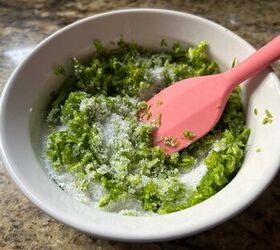 easy diy garlic scape salt recipe, a pink spatula mixing together chopped greens and coarse sea salt in a ramekin