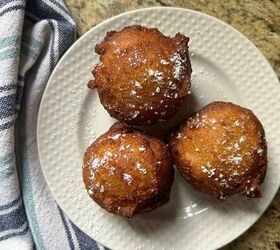 sourdough discard ricotta donuts with fresh milled flour, three fried donut balls on a white place sprinkled with powdered sugar