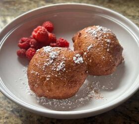 sourdough discard ricotta donuts with fresh milled flour, two Italian zeppole and raspberries on a white place sprinkled with powdered sugar