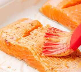 oven baked blackened salmon recipe, A pastry brush brushing melted butter and blackened seasoning on salmon