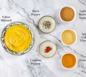 sweet and tangy carolina bbq sauce mustard based classic, Overhead view of small bowls filled with yellow mustard black pepper light brown sugar apple cider vinegar honey and cayenne pepper on a white marble surface