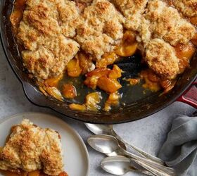 easy peach cobbler pound cake with brown butter glaze, looking down at the cast iron pan of peach cobbler with two plates with servings of the cobbler and ice cream along three spoons