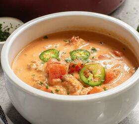 keto taco soup a flavorful and easy low carb meal, A bowl of Keto Taco Soup with chunks of tomato ground meat and sliced jalape os garnished with herbs A pot and a dish of chopped herbs are in the background