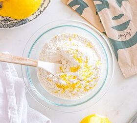 starbucks copycat lemon loaf, A bowl of flour and lemon zest with a spatula surrounded by lemons napkins and a white cloth