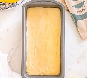 starbucks copycat lemon loaf, A loaf pan filled with lemon cake batter sits on a countertop next to fresh lemons and a paper napkin