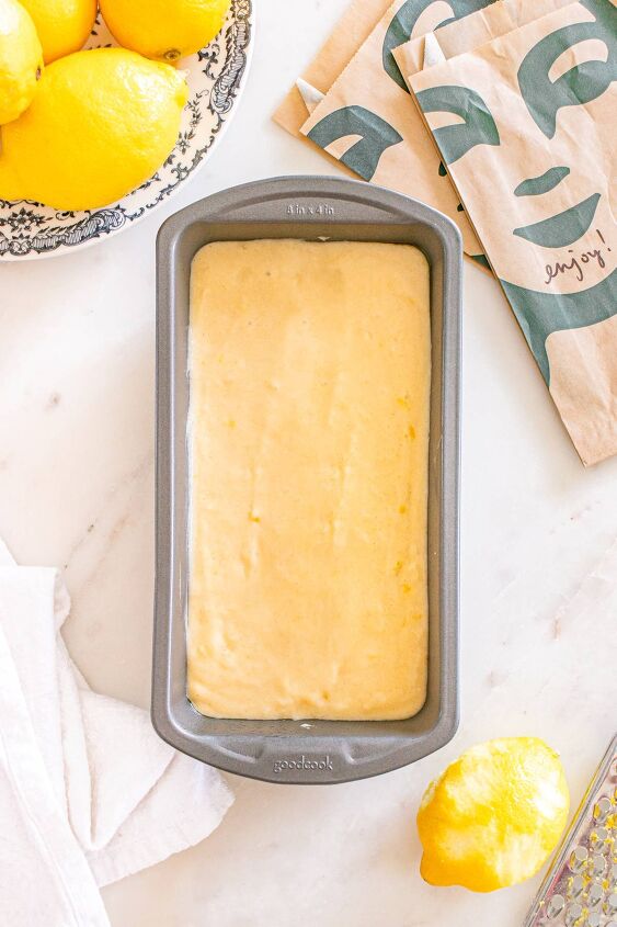 starbucks copycat lemon loaf, A loaf pan filled with lemon cake batter sits on a countertop next to fresh lemons and a paper napkin