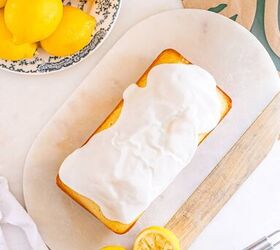 starbucks copycat lemon loaf, Iced lemon loaf on a board with whole and halved lemons a grater and a patterned plate nearby