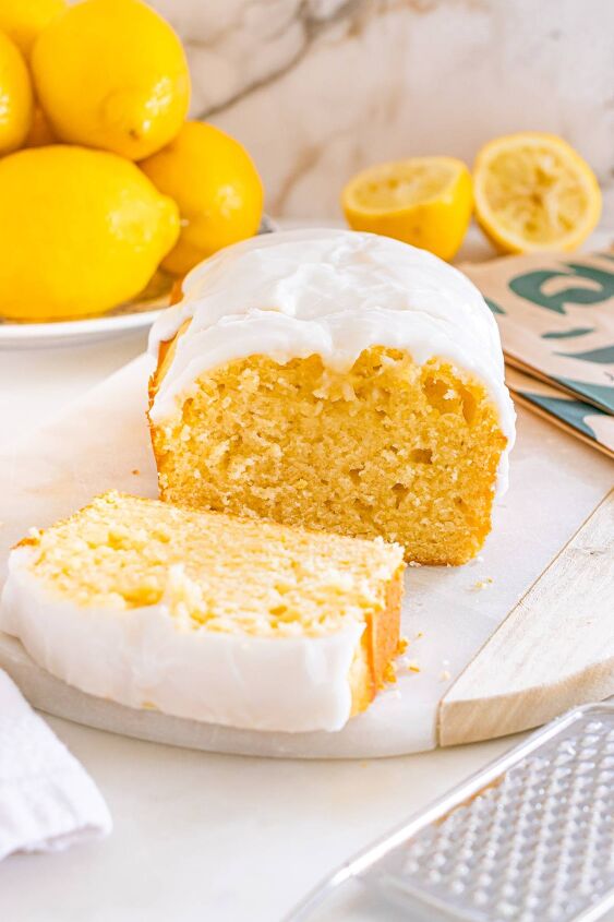 starbucks copycat lemon loaf, Lemon loaf cake with white icing sliced on a cutting board fresh lemons in the background