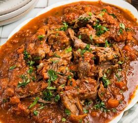 stracotto italian pot roast, A platter of shredded beef in tomato sauce garnished with chopped herbs next to mashed potatoes