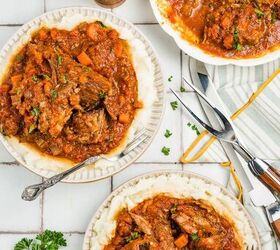 stracotto italian pot roast, Overhead view of plates with pot roast in tomato sauce garnished with parsley on a tiled surface