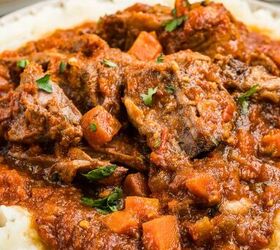 stracotto italian pot roast, Beef stew with carrots and tomato sauce served over mashed potatoes on a white plate